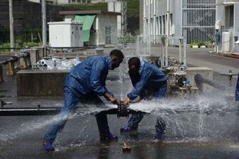 破裂した水道管を修理する研修員の写真