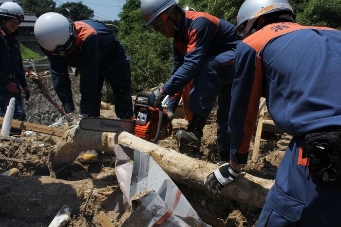 写真：流木をチェンソーで切断しています。