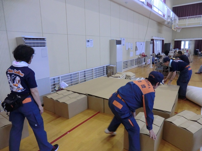 写真：避難所で段ボールベッドを作っています。