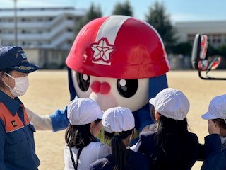広島市消防団マスコットキャラクターのひろピーがこどもと触れ合っている写真