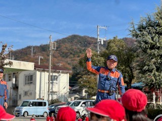 消防団員がこどもたちに手を振っている写真