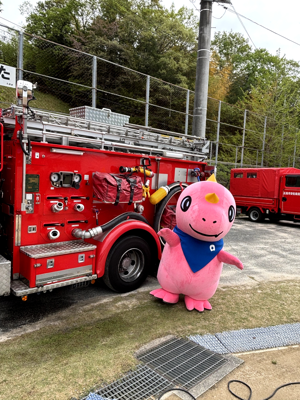 消防車の前で記念撮影するあみゴン