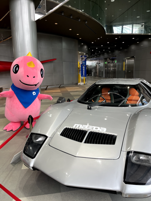 展示車の横で決めポーズをするあみゴン