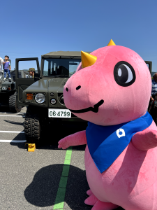 自衛隊の車の前でポーズをとるあみゴン