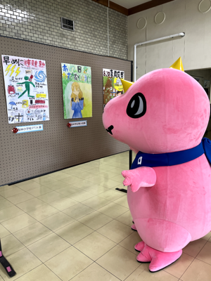 小学生のポスターを眺めるあみゴン
