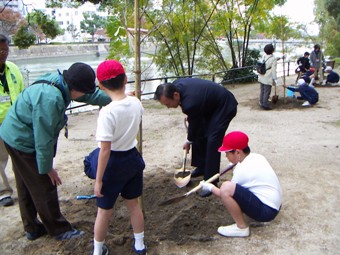 植樹活動を行う秋葉忠利広島市長と児童たち