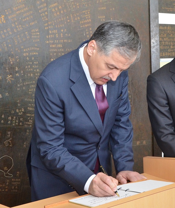 Minister Aslov writing a message on the guest book